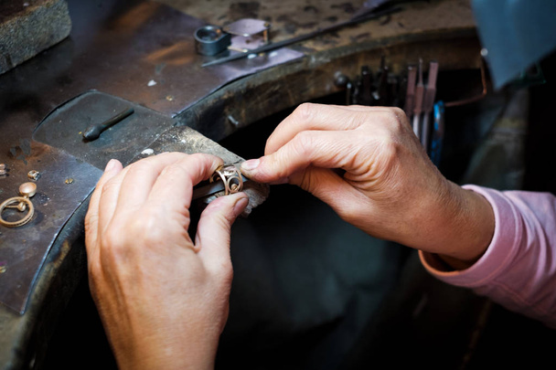 Joalheiro trabalhando com um arquivo de agulha um anel de ouro em uma antiga bancada de trabalho em oficina de jóias autênticas
 - Foto, Imagem