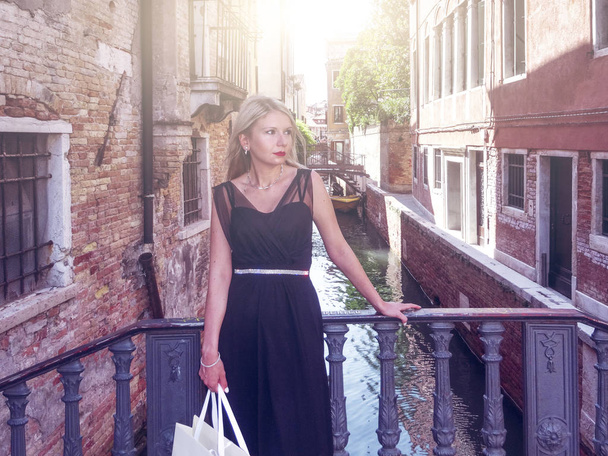 ヴェネツィア、イタリアのフィルター化イメージで日当たりの良い通りを歩いて黒いドレスの女 - 写真・画像