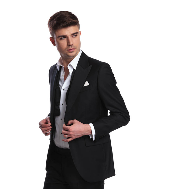 retrato del hombre de negocios abotonando su traje y mirando hacia un lado mientras está de pie sobre fondo blanco
 - Foto, imagen