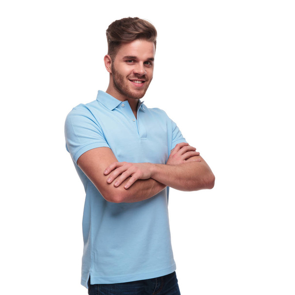 портрет уверенного молодого человека в рубашке для поло, стоящего на белом фоне со сложенными руками и улыбающимся
 - Фото, изображение