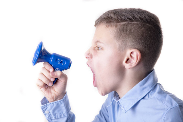Chico gritando muy fuerte en un pequeño megáfono azul con la boca abierta
 - Foto, imagen