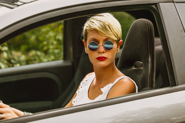 Młoda Blondynka atrakcyjna kobieta uśmiechając się i patrząc prosto podczas jazdy samochodem. - Zdjęcie, obraz