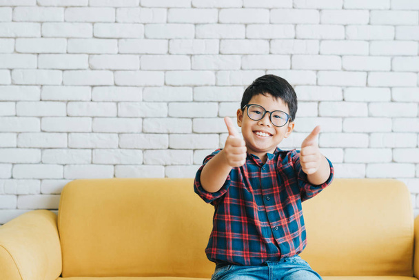 Gelukkig vrolijke Aziatische jongen tonen duimen omhoog op de Bank - Foto, afbeelding