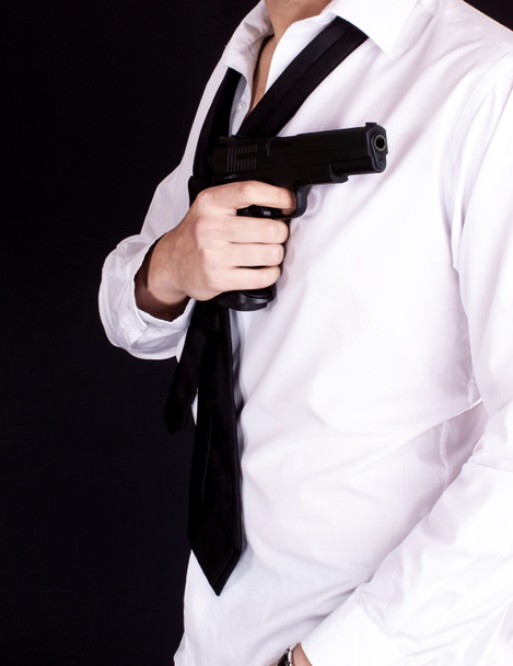 Человек в черном костюме держит пистолет в руке. Секретный агент, мафия, телохранитель
. - Фото, изображение