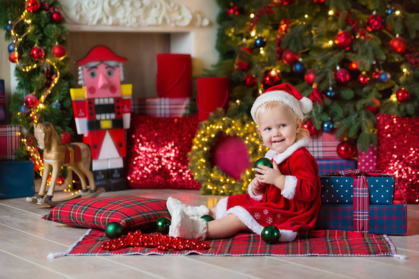 Merry Christmas and Happy Holidays Cute little child girl is decorating the Christmas tree indoors - Фото, зображення
