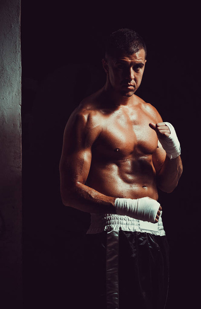 Muskularny mężczyzna młody bokser owijanie dłoni z bandażem. Koncepcja człowieka myśliwiec. - Zdjęcie, obraz