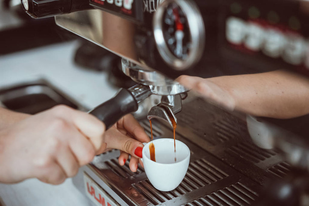 Професійний еспресо-машина, що наливає свіжу каву в білу керамічну чашку
 - Фото, зображення