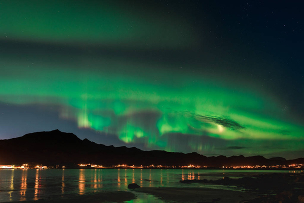 Aurora over sandy beach haukland, Kvalvika and Skagsanden with stones in Norway, Lofoten islands. Northern lights in Lofoten islands, Norway. Starry sky with polar lights. Night landscape with green - Photo, Image