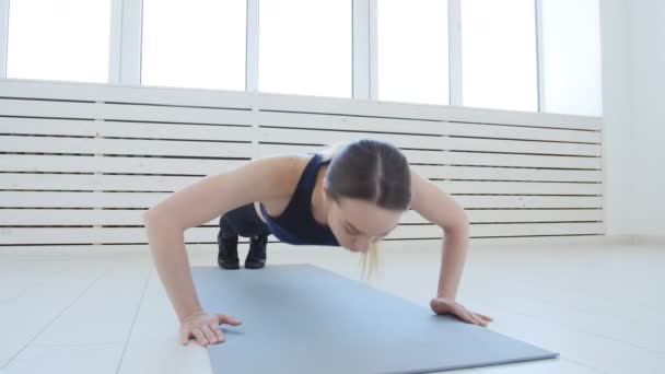 Concept de sport et de fitness à domicile. Jeune femme mince faisant des exercices de fitness dans un intérieur blanc
 - Séquence, vidéo