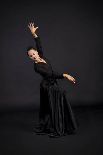 A young,smiling girl in black suit dancing modern choreography.Studio shot on dark background, isolated image. - 写真・画像