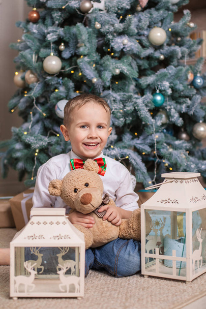 Radostné chlapce s jeho oblíbenou hračkou sedí pod vánoční stromeček - Fotografie, Obrázek