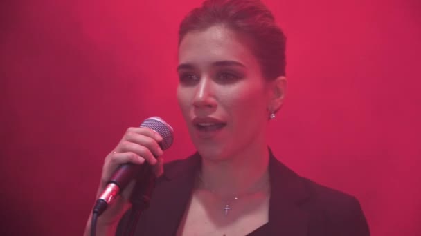 Close up van een meisje-zanger in muziekband het optreden van een lied tijdens show met rood licht en rook in de achtergrond. - Video
