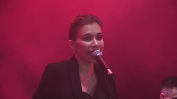 Zblízka dívka zpívá v hudební kapely provedení skladby během show se červené světlo a kouř v pozadí. - Záběry, video