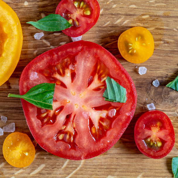 Viipaloidut tomaatit ja basilika puulaudalla
 - Valokuva, kuva