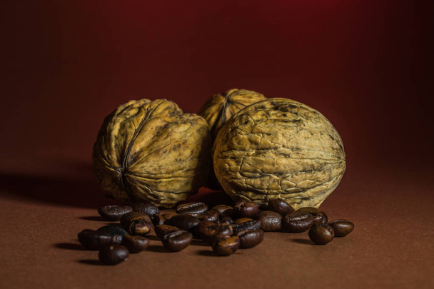 a small bottle with coffee beans and walnut on a brown background. - Foto, Imagem