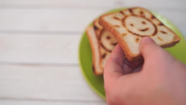 Detail of male hands spreading butter over a toasted bread slice, making a sandwich for breakfast. Selective focus on the knife and the hands - Záběry, video