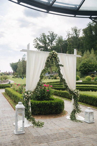 Weddind decoration on open air. Floral decor of a beautiful white arch. Beautiful beckground view of trees - Photo, Image