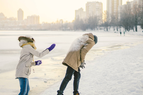 Les jeunes caucasiens amoureux couple hétérosexuel ont un rendez-vous en hiver près d'un lac gelé. Vacances actives Saint Valentin, jouer aux boules de neige et jouer à la joie
. - Photo, image