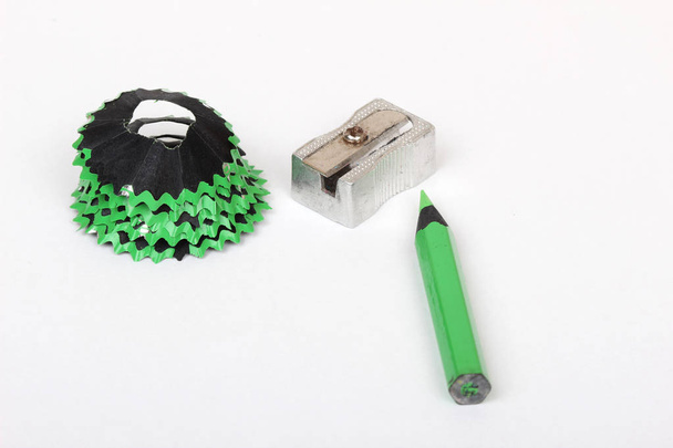 groene potlood en schaafsel op wit papier achtergrond - Foto, afbeelding
