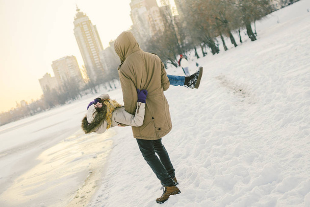 Téma szabadtéri tevékenységek télen. Szerető pár férfi és a nő kaukázusi öröm boldogság boldogság szerelem érzelmek a tó partján. A srác egy lány visel a gazdaságok. Valentin-napi ünnep - Fotó, kép