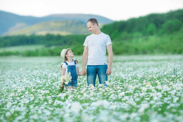 Young family in a field of flowers daises chamomile anjoy spa life happy together with cute faces in a village rustic motion. - Fotoğraf, Görsel