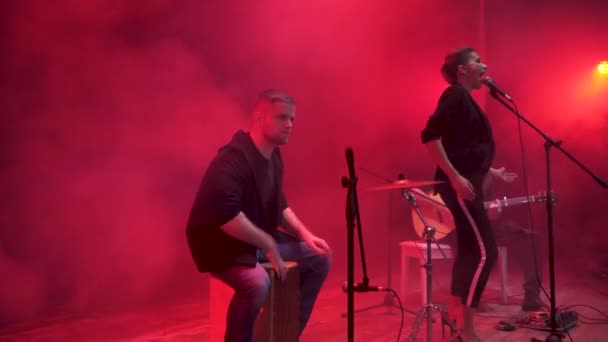 Μουσική μπάντα που εκτελεί στο στάδιο κόκκινο φως και καπνό στο παρασκήνιο. Τρεις μουσικοί - ντράμερ, κιθαρίστας και τραγουδιστής κορίτσι εκτέλεση μουσικής κατά τη διάρκεια του show. - Πλάνα, βίντεο