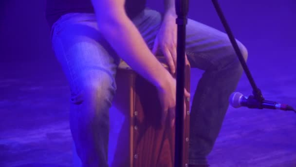 Primer plano de un baterista en la banda de música tocando en kahon en el escenario durante el espectáculo con luz azul y humo en el fondo
. - Metraje, vídeo