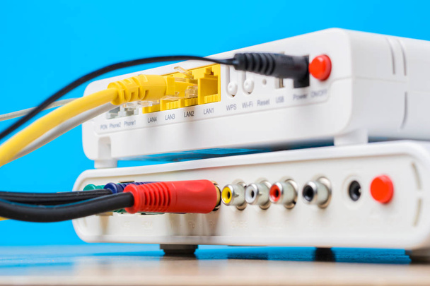 domowe routery bezprzewodowe z kabli ethernet podłączony na niebieskim tle, zbliżenie - Zdjęcie, obraz