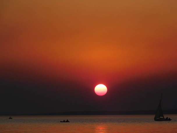 Atardecer el sol con tonos cobrizos y naranjas ilumina el horizonte - Foto, Imagem