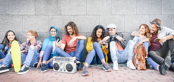 Gruppe multiethnischer Freunde, die sich im Freien amüsieren - Millennial-Jugendliche mit Mobiltelefonen, die Fotos machen und Musik mit Vintage-Stereoanlage hören - Konzept der Generation z, sozialer und jugendlicher Lebensstil - Foto, Bild
