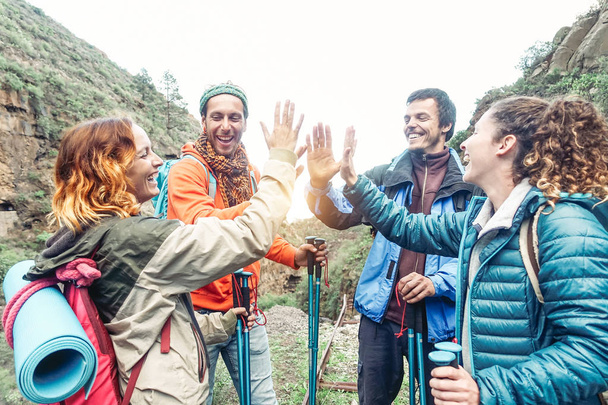 Grupo de amigos que empilham as mãos enquanto fazem excursão de trekking na montanha - Jovens turistas caminhando e explorando a natureza selvagem - Trekker, equipe, caminhada e conceito de pessoas de viagem
 - Foto, Imagem