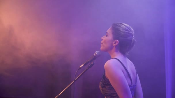 Stedicam は感情的にカラフルなライトと背景の煙で音楽バンドと一緒にステージで演奏の少女歌手に飛び回る。明るいコンサート舞台照明、煙や霧 - 映像、動画