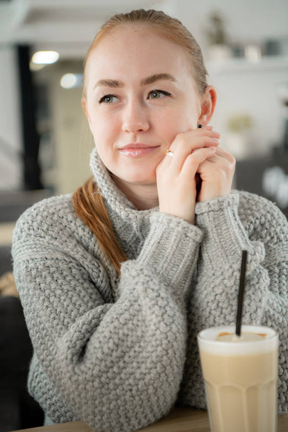 Coquete ruivo sorrindo jovem europeia sentada em um café com café
. - Foto, Imagem