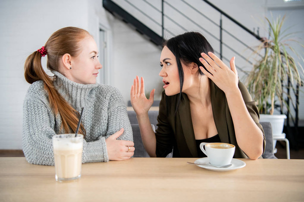 Freundinnen sitzen im Restaurant und fühlen sich gestört - Foto, Bild