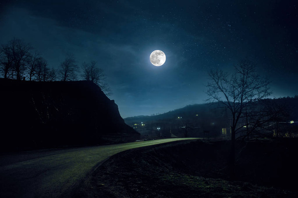 Mountain Road a través del bosque en una noche de luna llena. Paisaje nocturno escénico de carretera rural por la noche con luna grande
 - Foto, imagen