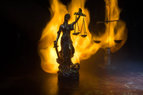The Statue of Justice - lady justice or Iustitia / Justitia the Roman goddess of Justice on a dark fire background. Selective focus - Photo, Image