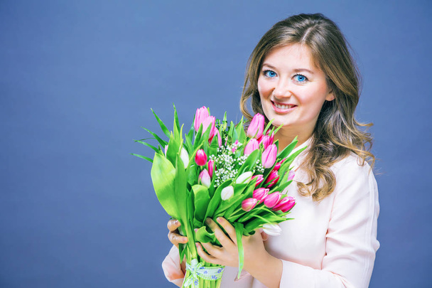 Cheerful young woman with bunny ears and Easter egg basket and tulips Flowers Looking at camera. - Фото, зображення