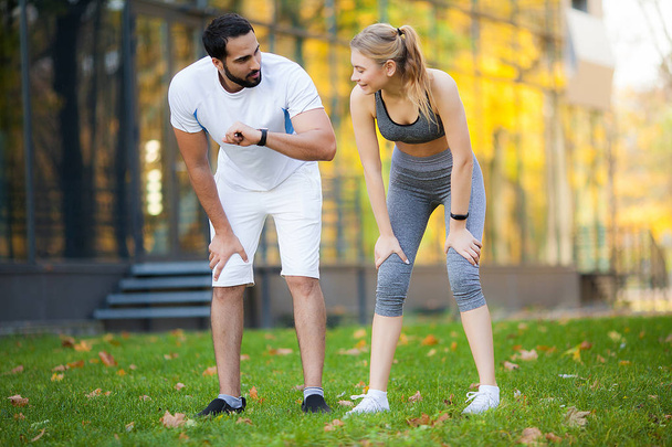 Fitness. Entrenador personal toma notas mientras la mujer hace ejercicio al aire libre
 - Foto, imagen