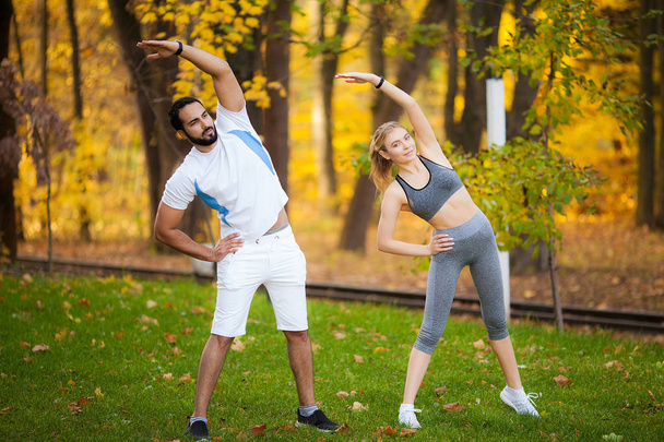 Fitness. Entrenador personal toma notas mientras la mujer hace ejercicio al aire libre
. - Foto, Imagen