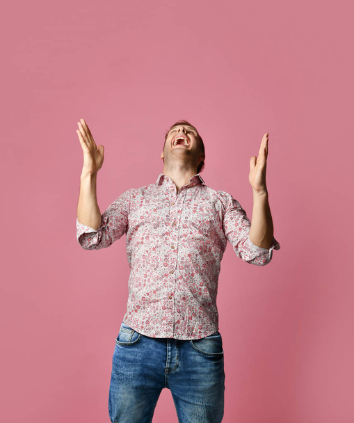 Jeune homme souriant heureux en chemise pointant les doigts vers le haut sur rose
  - Photo, image