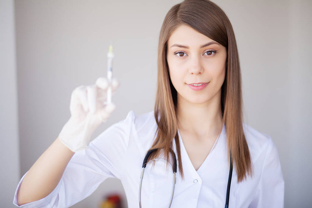 Female doctor or physician holding hypodermic syringe with injection - Фото, изображение