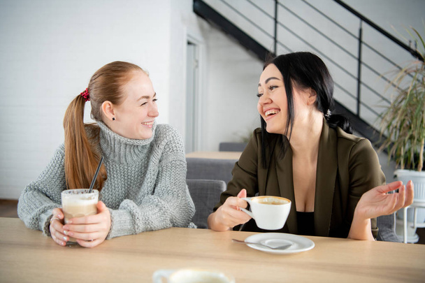 Δύο χαμογελαστοί μαθητές πίνουν καφέ στην καντίνα του κολεγίου. - Φωτογραφία, εικόνα