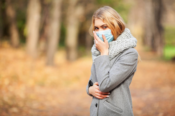 Resfriado y gripe. Mujer con mascarilla médica al aire libre
 - Foto, imagen