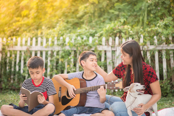 Yksinhuoltaja ja pojat soittaa kitaraa yhdessä hauskaa puistossa
   - Valokuva, kuva
