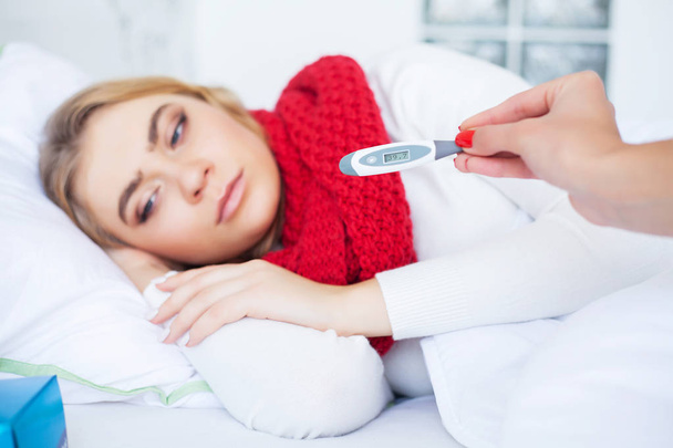 Cold And Flu. Sick woman lying on a bed with a thermometer - Photo, image