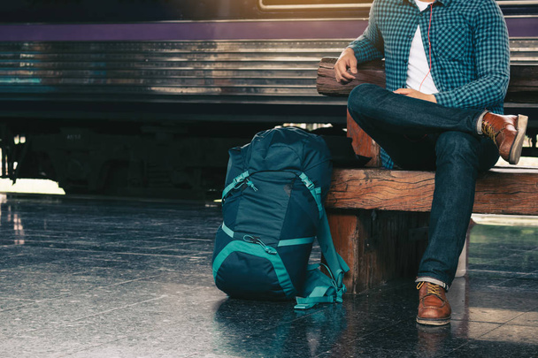 Backpacker man sitting on bench waiting at train station. - Photo, Image