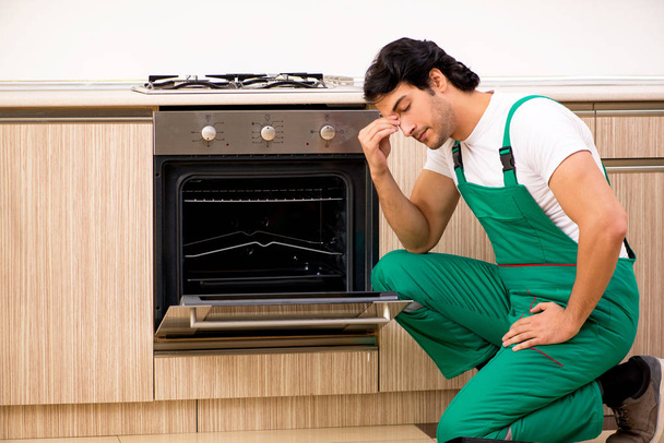 jovem empreiteiro reparação forno na cozinha  - Foto, Imagem