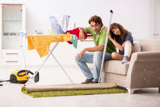 Marido ajudando perna ferida esposa em tarefas domésticas
  - Foto, Imagem