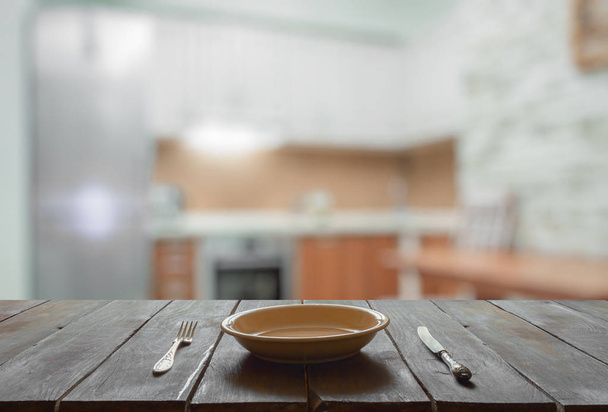 άδειο πιάτο με πιρούνι και μαχαίρι σε ξύλινο τραπέζι στην κουζίνα - Φωτογραφία, εικόνα