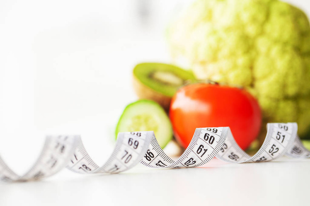 Diet. Fitness and healthy food diet concept. Balanced diet with vegetables. Fresh green vegetables, measuring tape on white background. Closeup - Photo, Image
